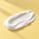 Texture della crema viso multivitaminica stesa su fondo giallo