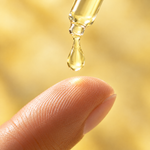Una goccia di siero viso multivitaminico che cade dal contagocce sul dito
