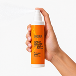 Spray solare SPF 50+ tenuto in mano mentre spruzza, per capire la misura